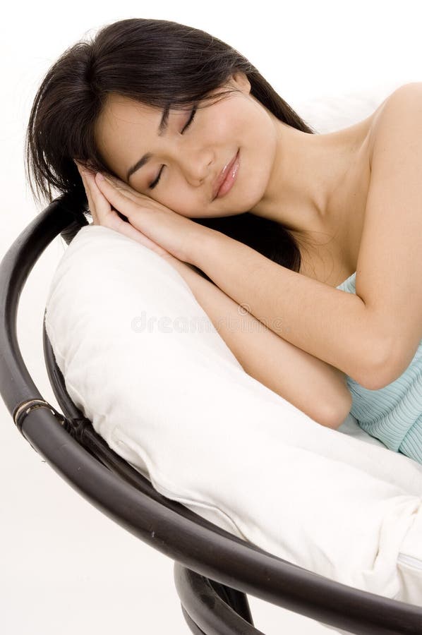 A pretty young asian woman takes a nap in a big comfortable chair. A pretty young asian woman takes a nap in a big comfortable chair