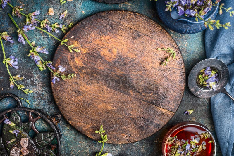 Aftrekselachtergrond met ronde houten raad, kop thee en diverse bloemen en het helen kruiden op donkere achtergrond, hoogste meni
