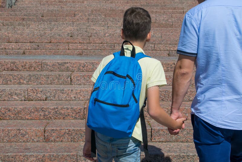 Against the backdrop of a ladder, the boy goes to school, holding his fathers hand