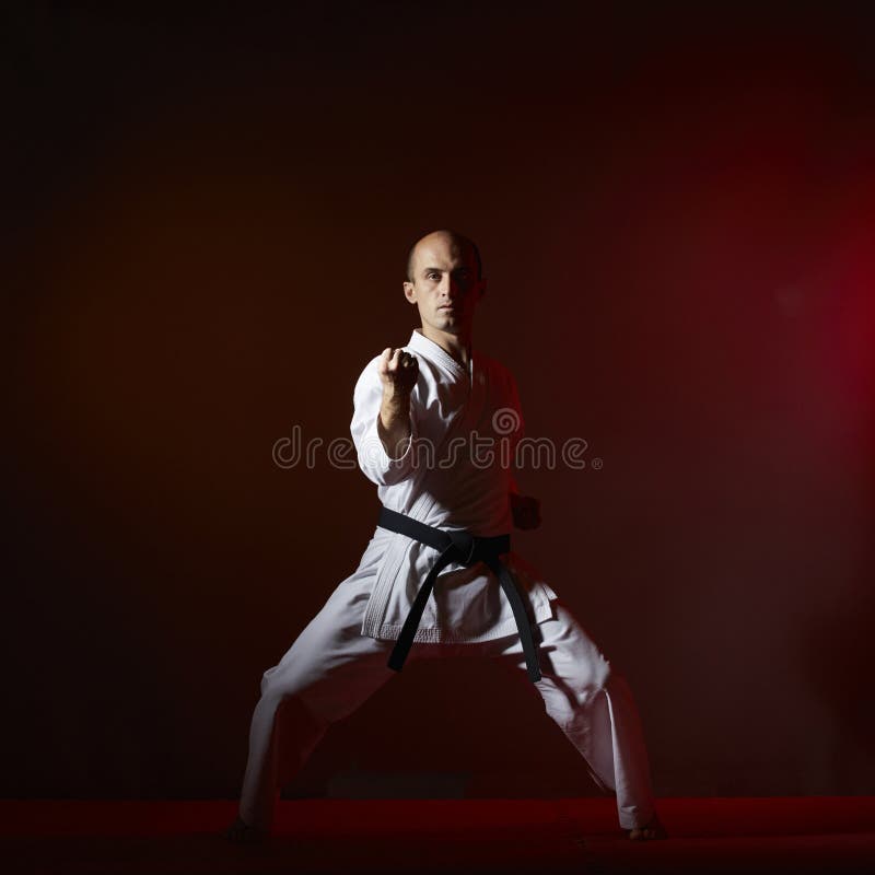 Against a dark background, an athlete does formal karate exercises. royalty free stock photo