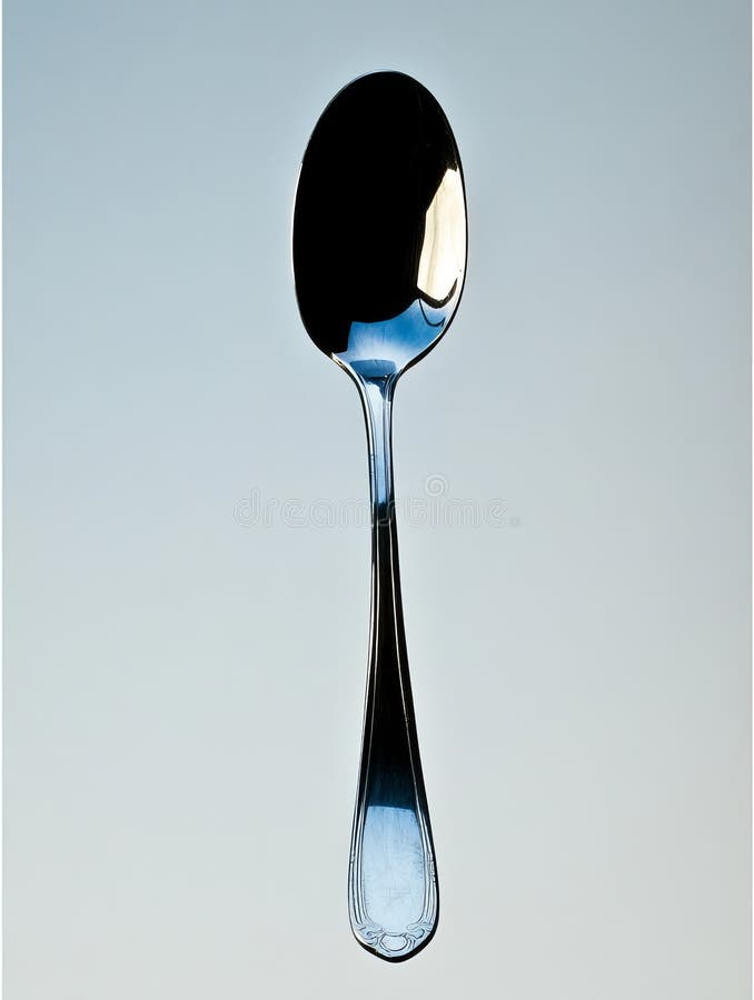 Against a pristine white backdrop, a tea spoon suspended with elegance showcases its sleek design and polished surface royalty free stock images