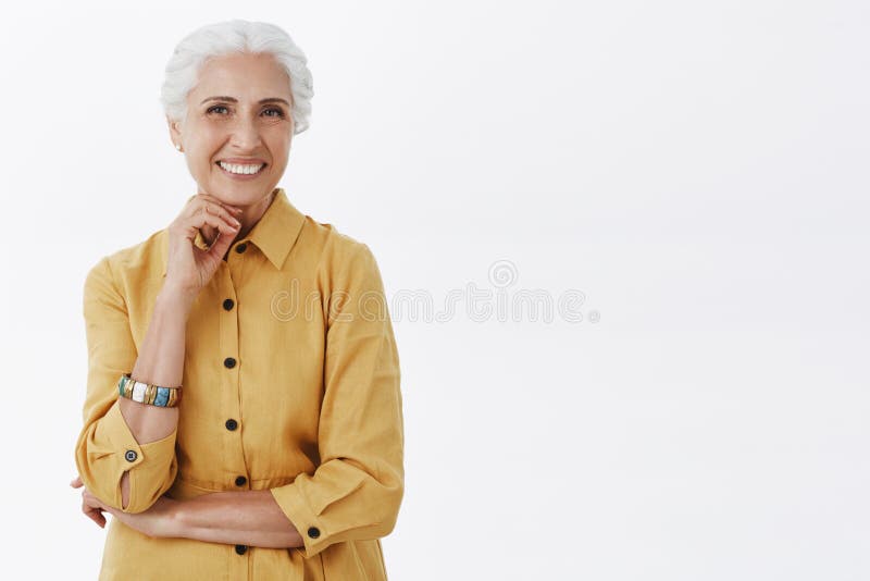 Age is nonsense. Portrait of happy charismatic stylish senior woman with white hair in trendy yellow coat posing with