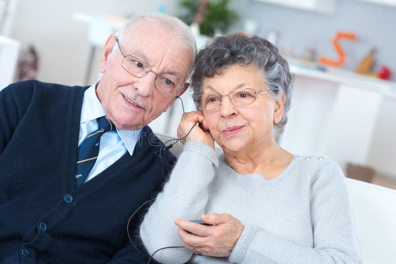 Aged couple sharing headphones listening to radio