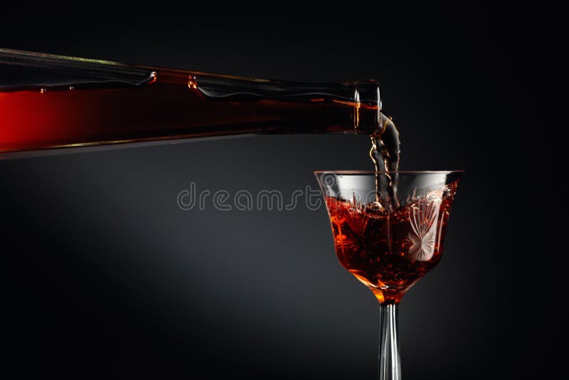 Aged golden fortified wine from the antique bottle being poured into a crystal glass