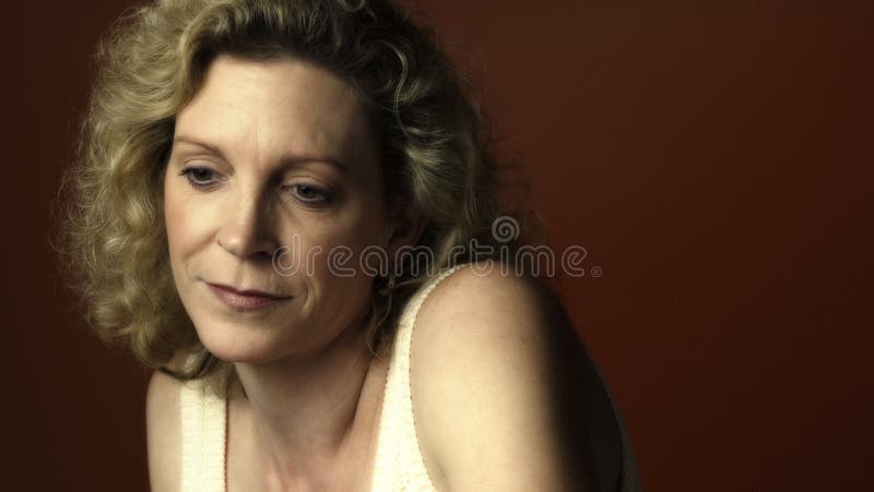 Portrait of a middle aged woman sitting in a chair and looking sad. Portrait of a middle aged woman sitting in a chair and looking sad