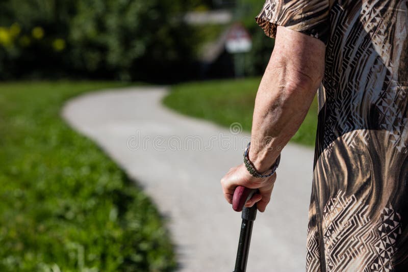 Old woman holding on to a cane walking outdoors. Old woman holding on to a cane walking outdoors