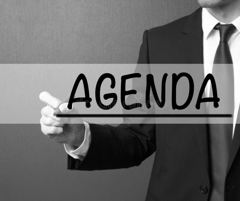 Agenda. Businessman in a suit with a marker writing on visual sc