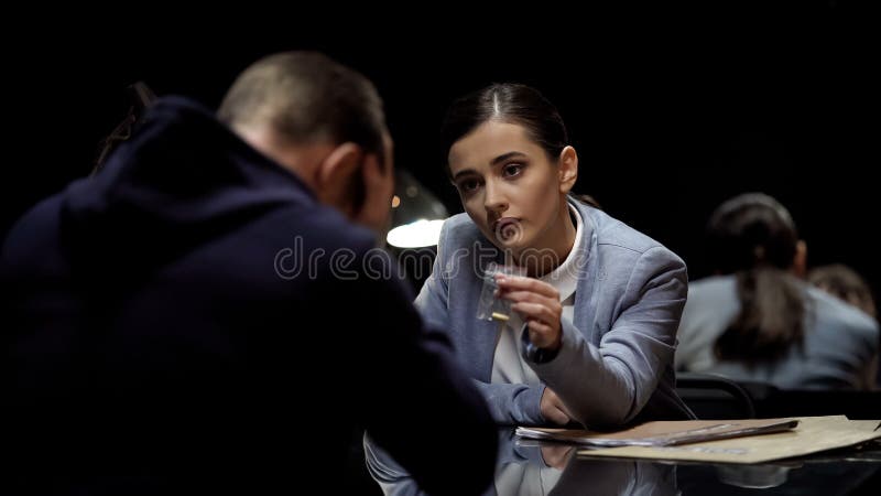Agent de police femelle montrant la preuve physique de balle, réaction suspecte de observation image stock Agent de police femelle montrant la preuve physique de balle, réaction suspecte de observation image stock