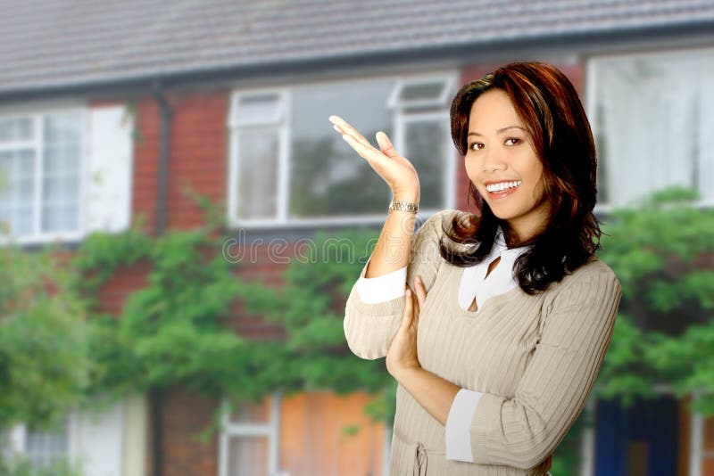 Attractive and friendly housing agent presenting a beautiful property in her background. Attractive and friendly housing agent presenting a beautiful property in her background.