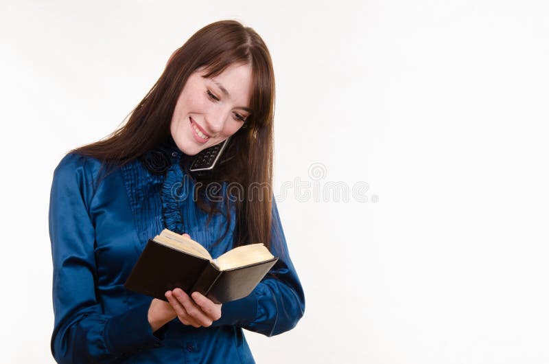 Beautiful young girl talking on the phone and writes notes in notebook. Beautiful young girl talking on the phone and writes notes in notebook