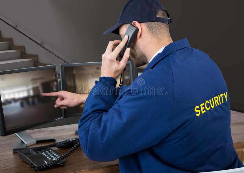 Agente de segurança em seu escritório que telefona e que aponta a algo na tela imagem de stock Agente de segurança em seu escritório que telefona e que aponta a algo na tela imagem de stock