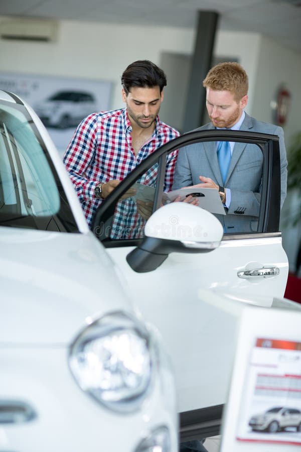 Agente dell'automobile che mostra il cliente del maschio del veicolo immagini stock Agente dell'automobile che mostra il cliente del maschio del veicolo immagini stock