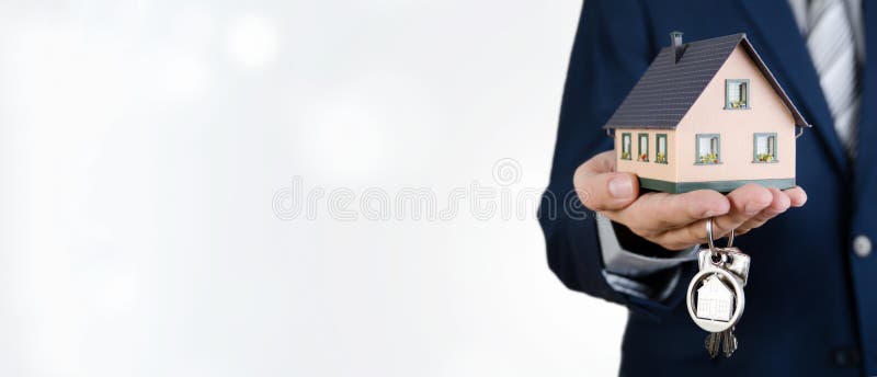 Agente immobiliare con le chiavi domestiche e la miniatura della casa