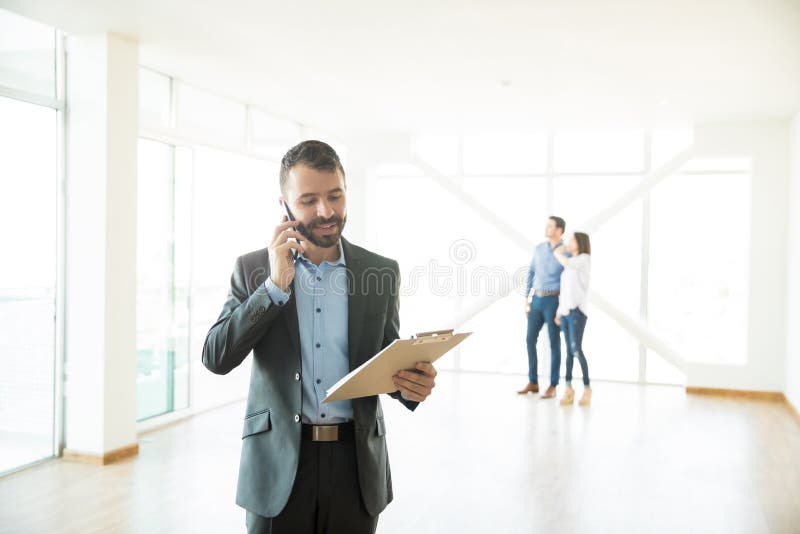 Agente immobiliare Using Mobile Phone a nuova casa immagine stock Agente immobiliare Using Mobile Phone a nuova casa immagine stock