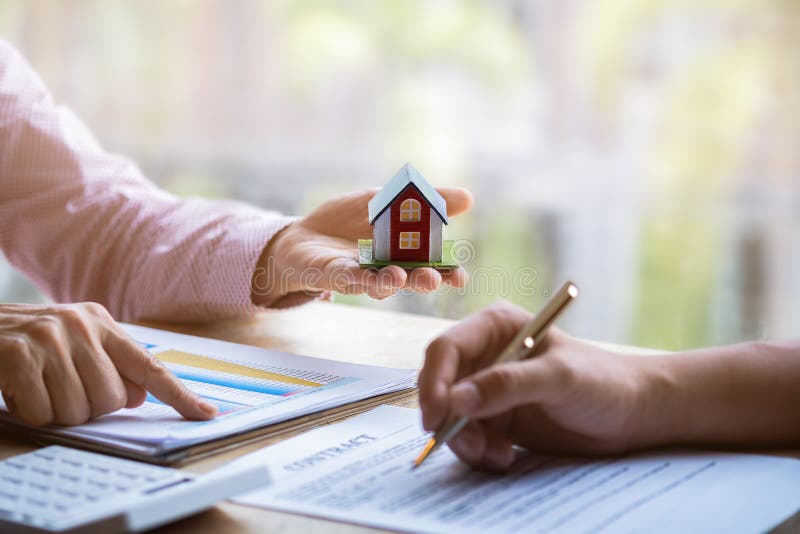 Agente imobiliário que aponta o dedo no documento que mostra o custo total que assina um documento de papel para a casa de compra