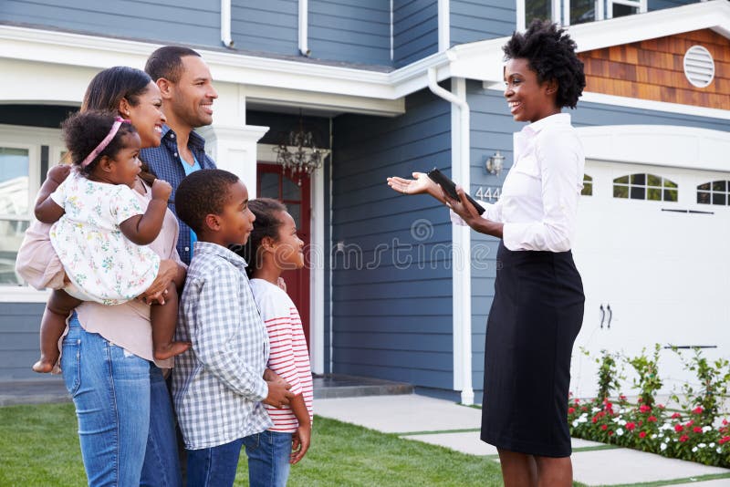 Agente inmobiliario que muestra a una familia una casa, más cercana adentro fotos de archivo Agente inmobiliario que muestra a una familia una casa, más cercana adentro fotos de archivo