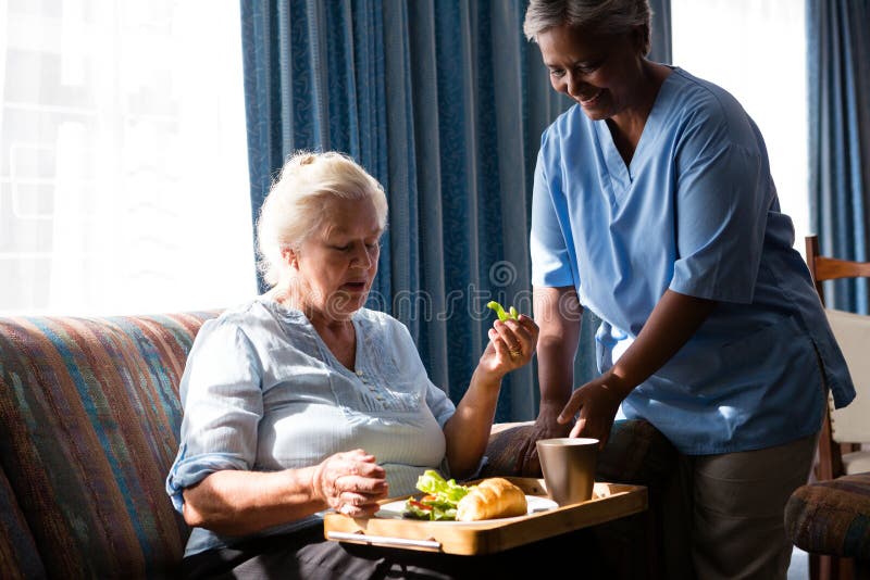 Aggiusti la donna senior facente una pausa che mangia l'alimento alla tavola immagine stock Aggiusti la donna senior facente una pausa che mangia l'alimento alla tavola immagine stock