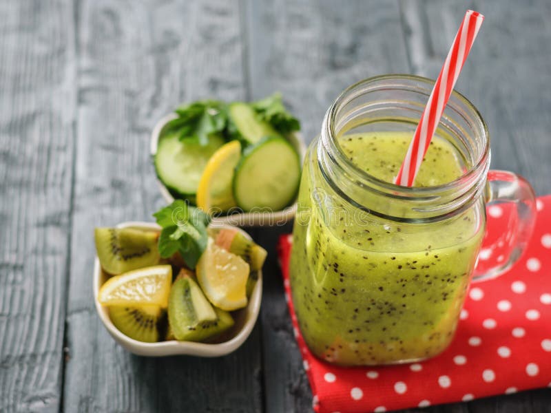 Aggredisca con il frullato appena fatto del kiwi su uno straccio e su un prezzemolo rossi su una tavola nera rustica. Aggredisca con il frullato appena fatto del kiwi su uno straccio rosso su una tavola rustica Bevanda vegetariana sana e nutriente della frutta e delle verdure fresche