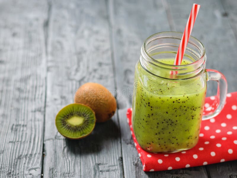 Aggredisca con il frullato appena fatto del kiwi su uno straccio rosso su una tavola di legno rustica fotografie stock