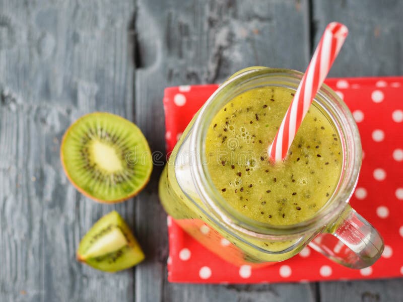 Aggredisca con il frullato appena fatto del kiwi su uno straccio rosso su una tavola rustica La vista dalla parte superiore fotografia stock