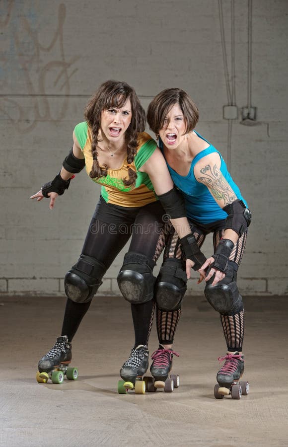 Aggressive women roller derby skaters threatening with a pose. Aggressive women roller derby skaters threatening with a pose