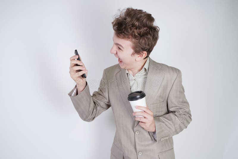 Aggressiver kaukasischer Jugendlicher schreit in das intelligente Telefon und hält einen Papiertasse kaffee in seiner Hand Studen stockbilder Aggressiver kaukasischer Jugendlicher schreit in das intelligente Telefon und hält einen Papiertasse kaffee in seiner Hand Studen stockbilder