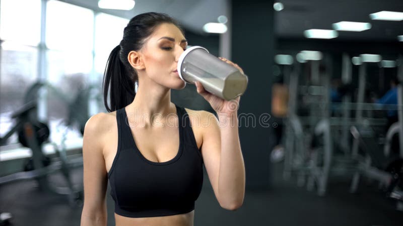 Agitação bebendo da proteína da mulher desportiva após o exercício, nutrição do ganho do músculo, saúde