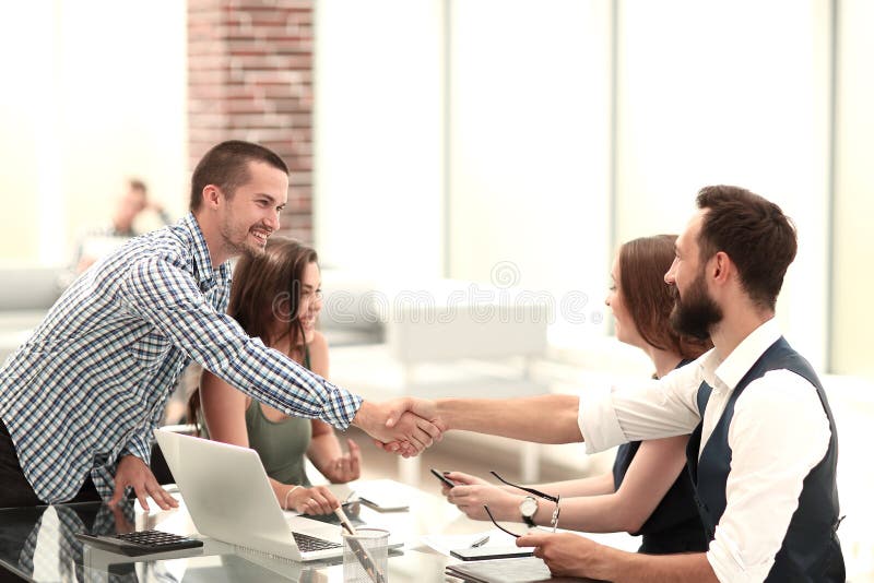 A agitação de sorriso dos sócios comerciais cede a mesa imagens de stock A agitação de sorriso dos sócios comerciais cede a mesa imagens de stock