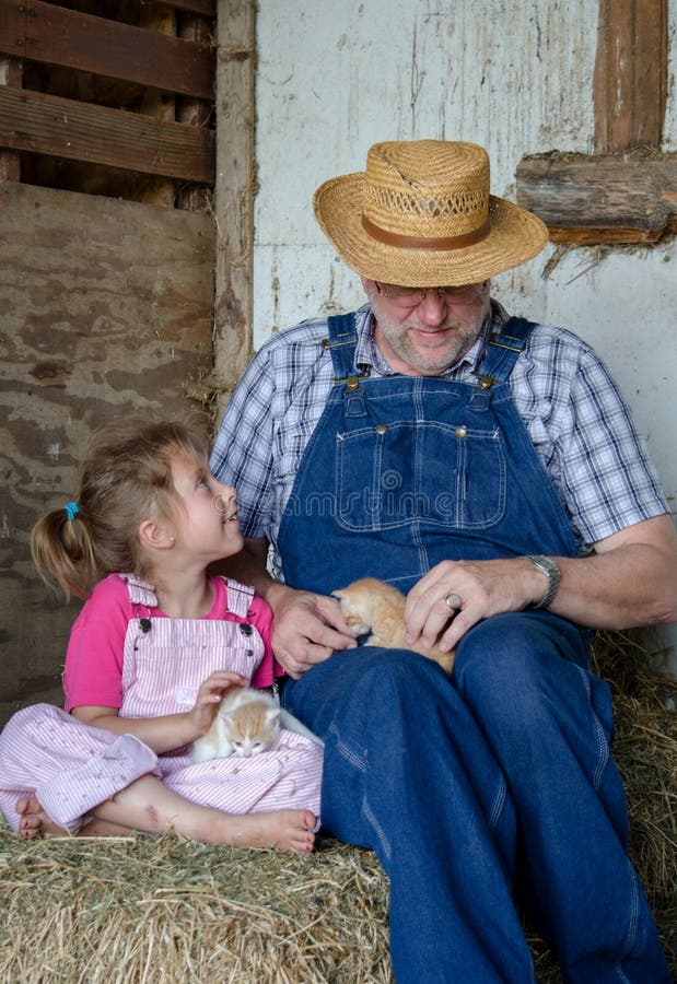 Grandpa site on bales of straw with his granddaughter and new kittens just born in the barn. Grandpa site on bales of straw with his granddaughter and new kittens just born in the barn