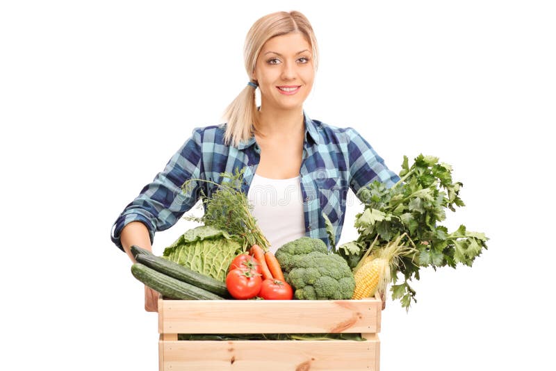 Young female farmer posing behind a crate full of fresh vegetables isolated on white background. Young female farmer posing behind a crate full of fresh vegetables isolated on white background