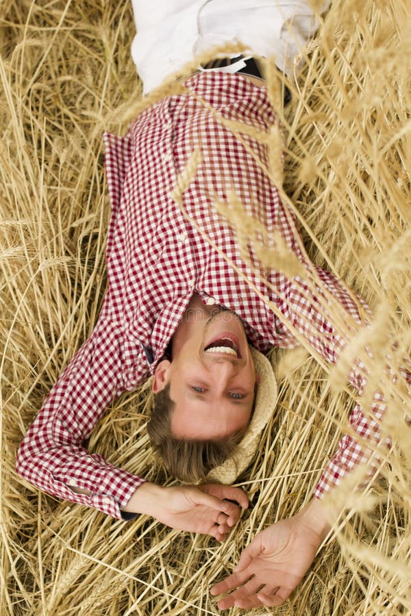 Agricoltore maschio felice deposto su pedali d'orzo e rilassato presso il prato d'orzo. giovane agronomo steso sui fusti di frumen immagini stock libere da diritti