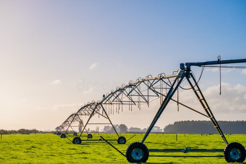 Agricoltura, irrigazione moderna. spruzzatore per acqua sul prato verde con cielo azzurro e luce calda. I fotografia stock libera da diritti Agricoltura, irrigazione moderna. spruzzatore per acqua sul prato verde con cielo azzurro e luce calda. I fotografia stock libera da diritti