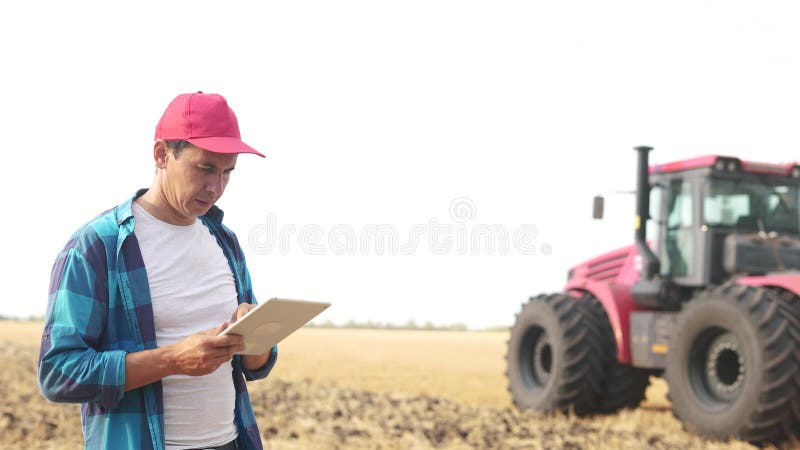 Agricultor num campo de trigo. conceito de empresa agrícola. um agricultor experiente caminha pelo campo de trigo com tablet em