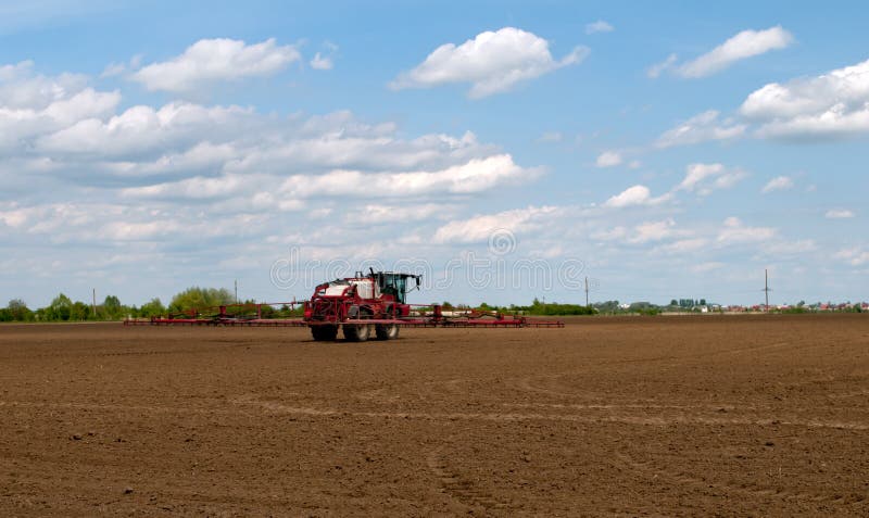 Agricultural fertilizer spreader spraying dry fertilizer on farm fields