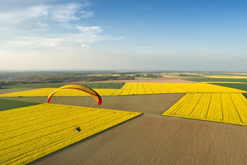Agricultural landscape of a rapeseed field flown over by a motorized paraglider and blue sky horizon stock photo Agricultural landscape of a rapeseed field flown over by a motorized paraglider and blue sky horizon stock photo