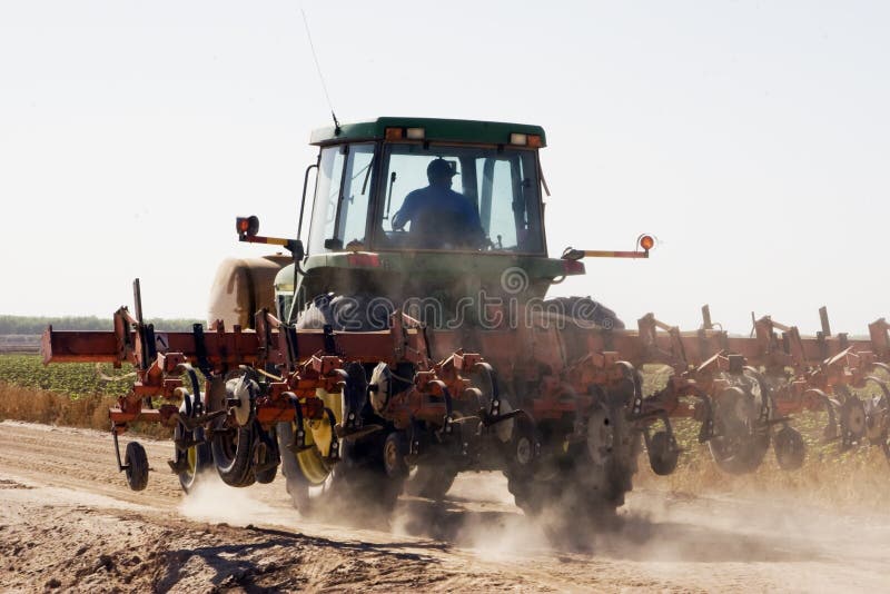 Farm tractor drives along dry dusty desert farm corn field. Farm tractor drives along dry dusty desert farm corn field