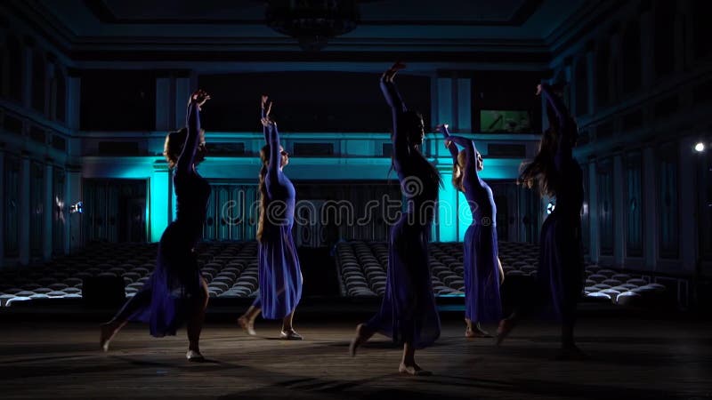 Agrupar jóvenes bailarinas hábiles bailando ballet moderno en el escenario de una gran sala Niñas mirando al auditorio Vestir metrajes