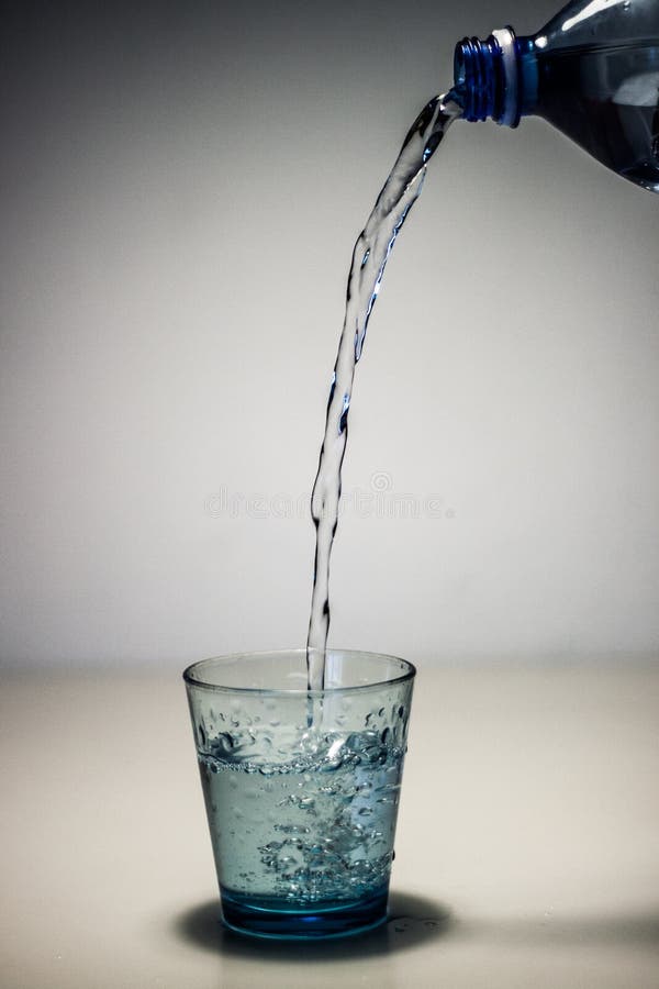 Agua fresca de la bebida de la botella en vidrio azul foto de archivo libre de regalías Agua fresca de la bebida de la botella en vidrio azul foto de archivo libre de regalías