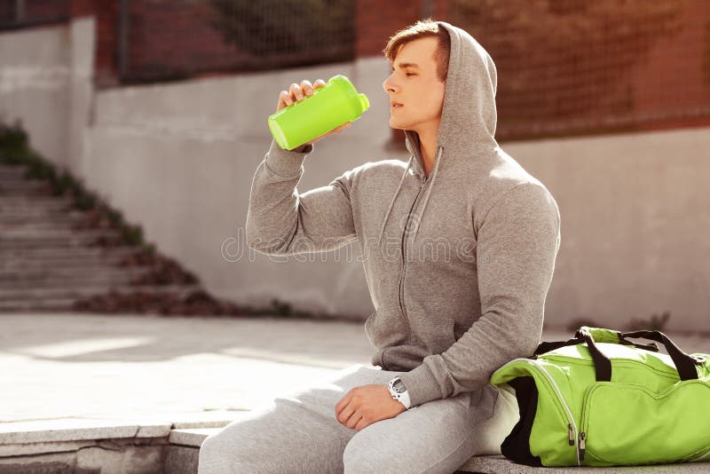 Agua potable del hombre activo joven, al aire libre Coctelera que se sostiene masculina muscular hermosa imagen de archivo libre de regalías Agua potable del hombre activo joven, al aire libre Coctelera que se sostiene masculina muscular hermosa imagen de archivo libre de regalías