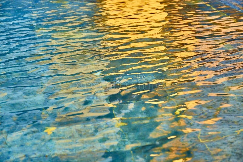 Agua transparente de la piscina con reflexiones del sol