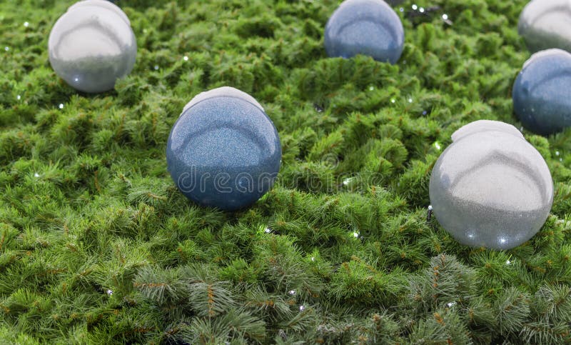 A textured surface made of green pine needles, a part of a Christmas tree, balls and a luminous garland. A textured surface made of green pine needles, a part of a Christmas tree, balls and a luminous garland.