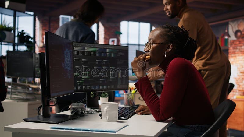 Irked AI startup engineer eating snack while waiting code to finish compiling stock photos