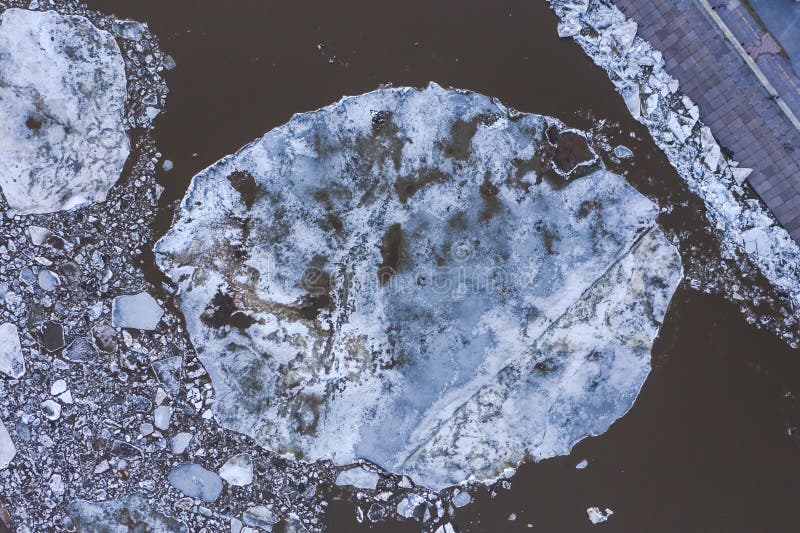 Aierial view from the top down on ice floes floating on the river. The ice drift in spring time. Camera looking down. Close-up of a large ice floe.