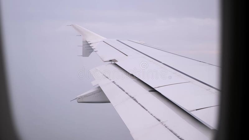 Aile d'un avion avec volets ouverts à l'atterrissage. Zone de turbulence. Vue sur une aile d'avion dans un ciel nuageux à travers banque de vidéos