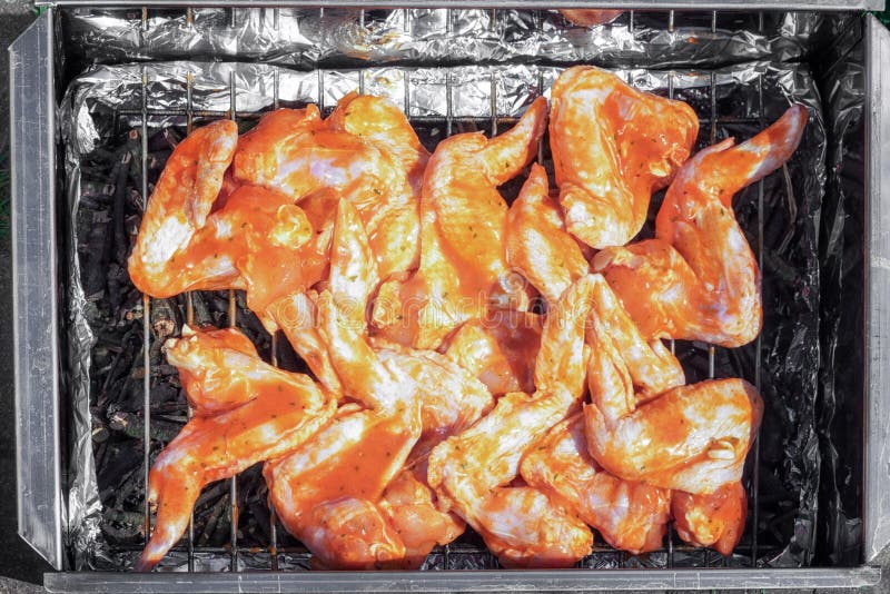 Ailes de poulet crues dans une marinade sur un fumoir photo stock Ailes de poulet crues dans une marinade sur un fumoir photo stock