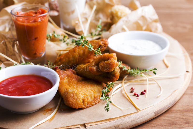 Ailes de poulet cuites au four épicées avec des apéritifs et des sauces sur rond photo libre de droits Ailes de poulet cuites au four épicées avec des apéritifs et des sauces sur rond photo libre de droits