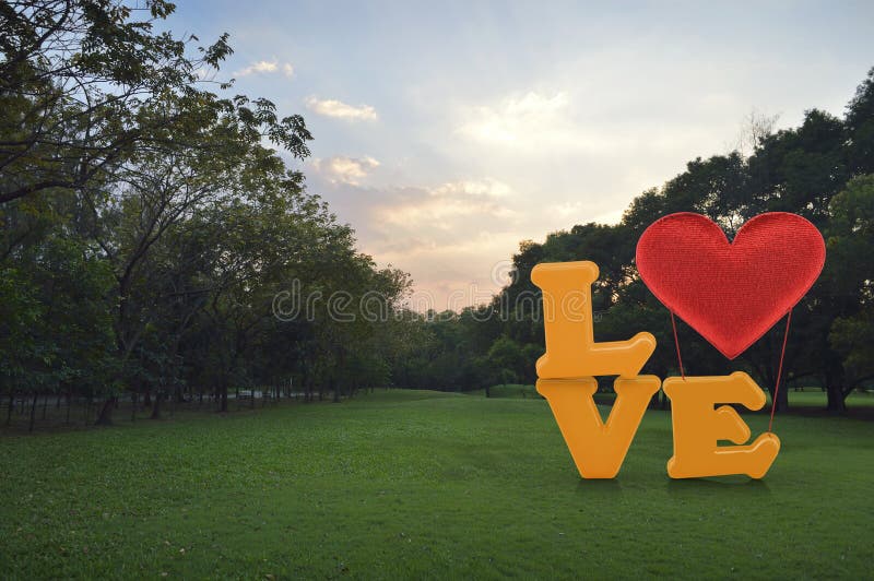 Aimez le mot avec le ballon de forme de coeur sur l'herbe verte en parc photos stock Aimez le mot avec le ballon de forme de coeur sur l'herbe verte en parc photos stock