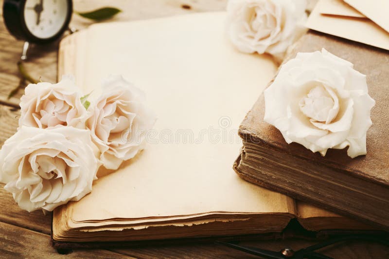 Retro still life with pale rose flowers and open book. Nostalgic composition on old wooden table. Retro still life with pale rose flowers and open book. Nostalgic composition on old wooden table.
