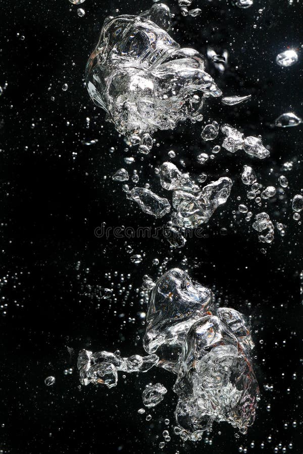 Air bubbles rising in water against a black background.