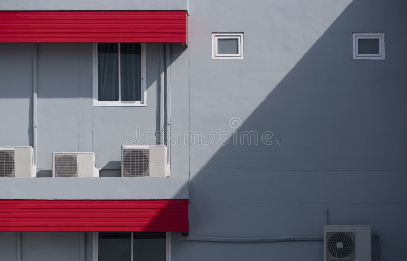 Air compressors with pipelines and glass windows on red and gray office building wall in modern style